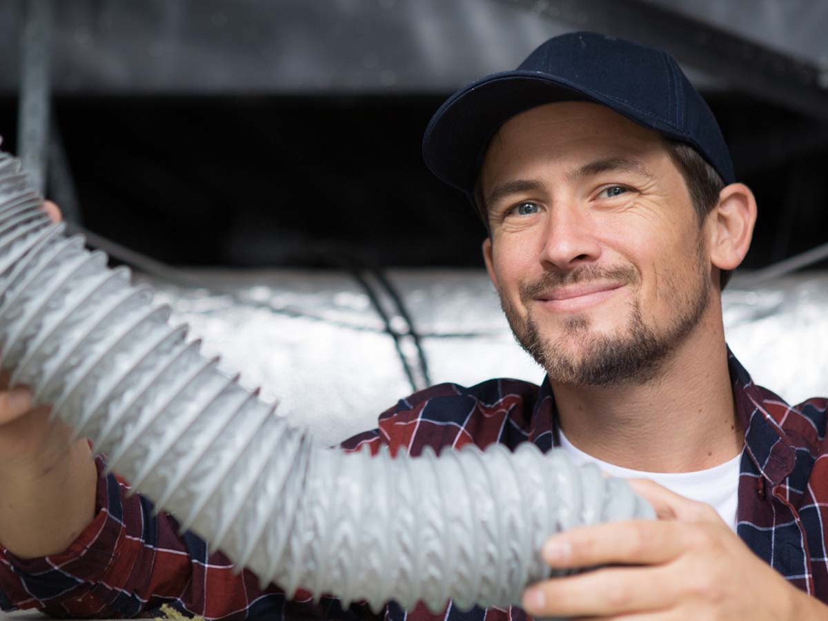 An image of a man holding a repair part and smiling.