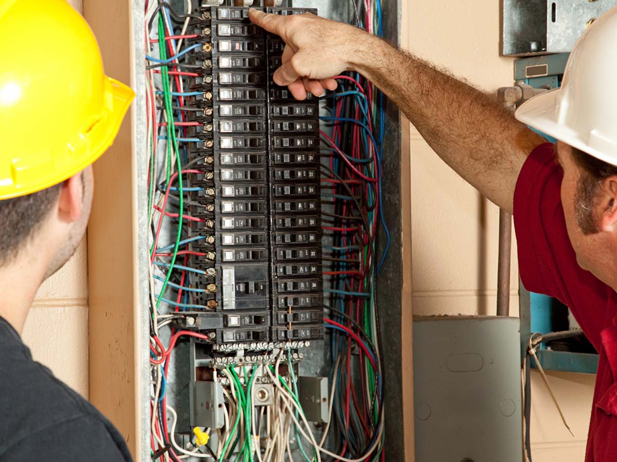 An image of two men looking at a circuit breaker.