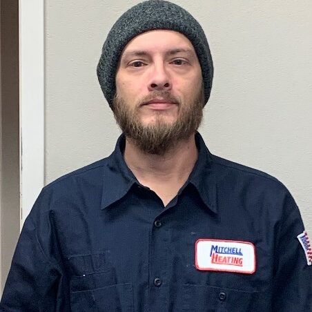 Portrait of Erik McCarty, a member of the service team at Mitchell Heating, wearing a beanie and a dark blue uniform.