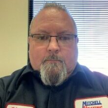 Portrait of Shawn Poole, Service Fleet Manager at Mitchell Heating, wearing a dark blue uniform and glasses.